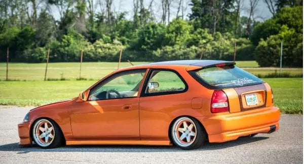 Modified orange car showcasing the lowering car pros and cons with an aggressive stance and unique wheels