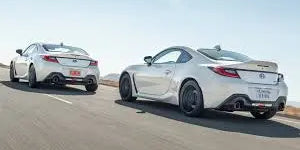Subaru BRZ vs Toyota GR86 comparison showcasing two sleek sports cars on a scenic road