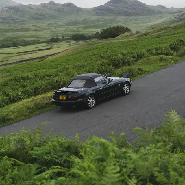A classic Mazda car parked on a scenic road, reflecting on Mazda car history and design evolution