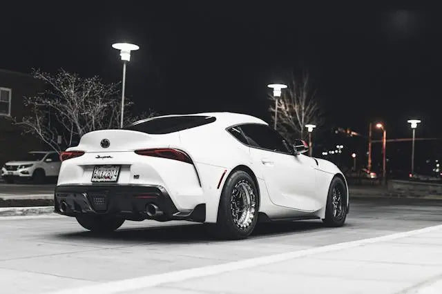 Toyota history and evolution showcased with a modern white sports car against a nighttime city backdrop