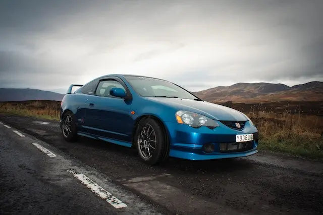Customized Acura RSX showcasing performance upgrades on a scenic road